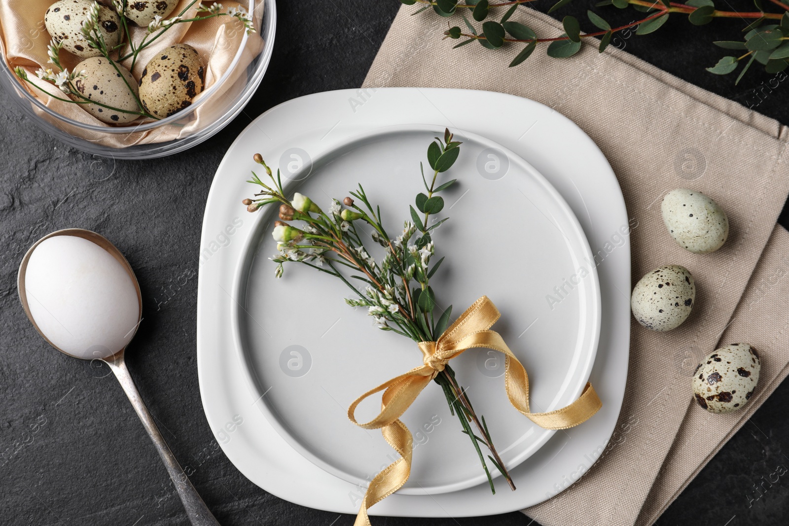 Photo of Festive Easter table setting with eggs and floral decoration on dark background, flat lay