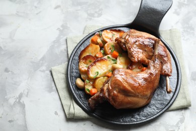 Photo of Tasty cooked rabbit meat with vegetables on light grey table, above view. Space for text