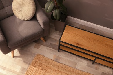 Photo of Wooden cabinet and comfortable armchair near grey wall in room, above view