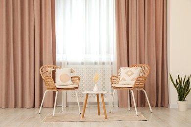 Photo of Living room with pastel window curtains, wooden table and rattan chairs