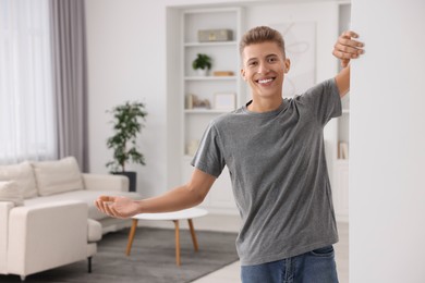 Photo of Happy man welcoming near white wall at home. Invitation to come in room