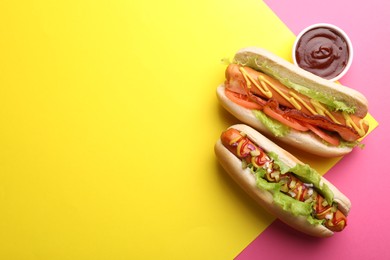 Photo of Delicious hot dogs with lettuce and sauces on color background, flat lay. Space for text