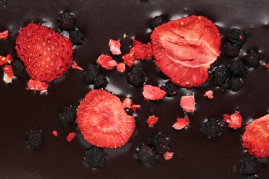 Photo of Chocolate bar with freeze dried berries as background, closeup