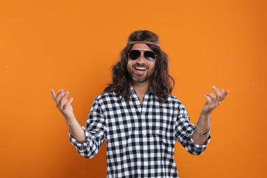 Photo of Hippie man in sunglasses on orange background