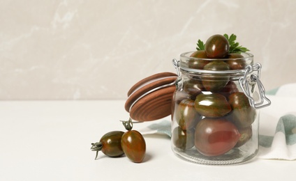 Photo of Pickling jar with fresh tomatoes on white table. Space for text