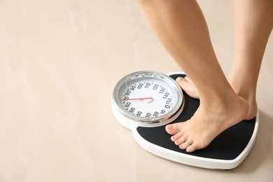 Photo of Woman standing on floor scales indoors, space for text. Overweight problem