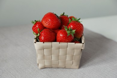 Photo of Fresh juicy strawberries in wicker basket on table, closeup
