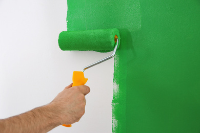 Photo of Man painting white wall with green dye, closeup. Interior renovation