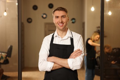 Photo of Portrait of professional hairdresser wearing apron in beauty salon
