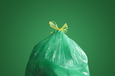 Photo of Trash bag full of garbage on green background