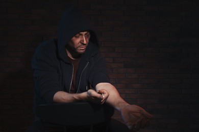 Photo of Addicted man taking drugs on dark background