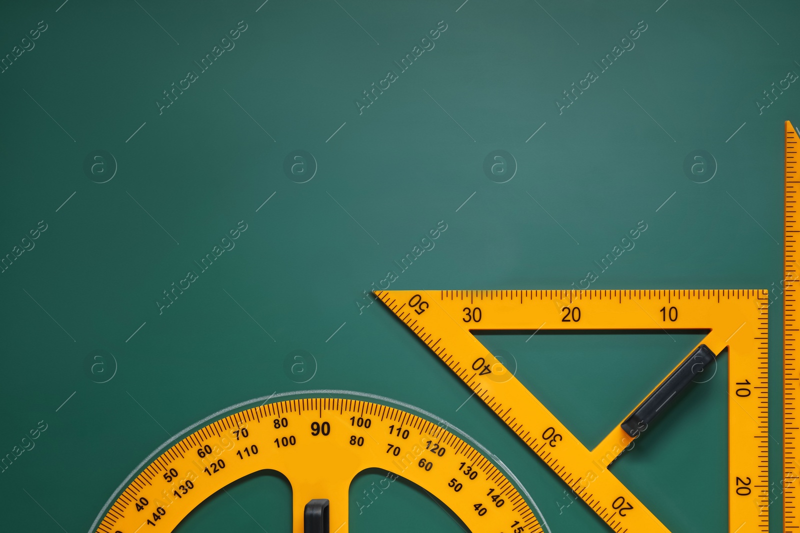 Photo of Protractor and triangles on green chalkboard, flat lay. Space for text