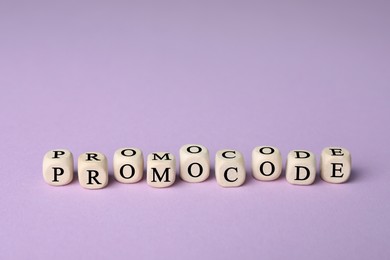 Wooden cubes with words Promo Code on violet background