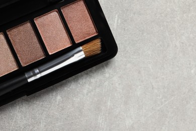Photo of Beautiful eye shadow palette with brush on grey textured table, top view. Space for text