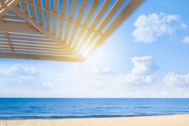 Image of Sun protection wooden umbrella on beach near sea