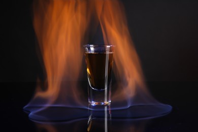 Photo of Flaming alcohol drink in shot glass on dark background