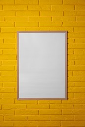 Photo of Empty frame on yellow brick wall. Mockup for design