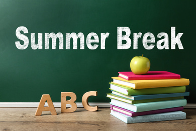 Image of Books, letters, apple near chalkboard with inscription Summer Break. School Holidays 