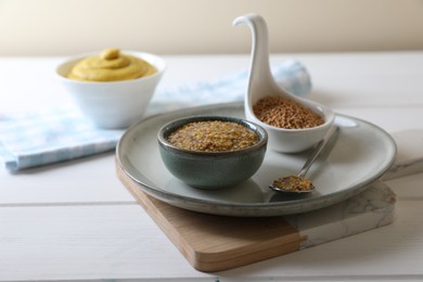 Photo of Bowl and spoon of whole grain mustard on white wooden table. Space for text