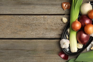 Photo of Plate with fresh onion bulbs, leeks and garlic on wooden table, flat lay. Space for text