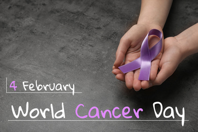 Image of Woman holding purple awareness ribbon on grey background, closeup. World Cancer Day