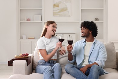 Photo of Happy couple with glasses of wine on sofa with wooden armrest table at home