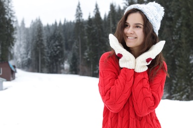 Photo of Happy young woman in warm clothes outdoors, space for text. Winter vacation