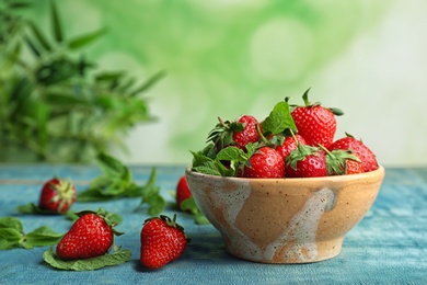 Photo of Bowl with ripe red strawberries and mint on wooden table