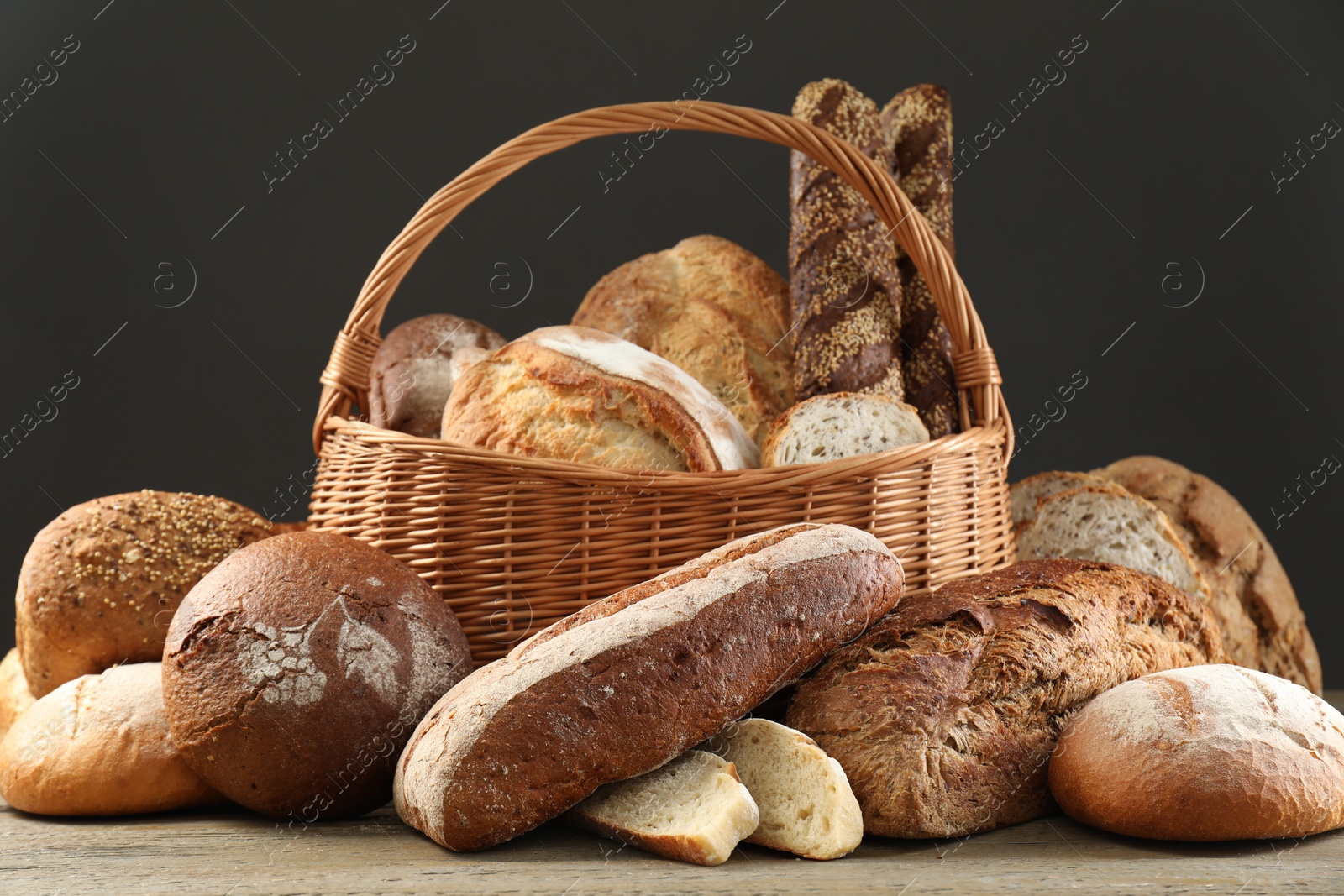 Photo of Wicker basket with different types of fresh bread on wooden table