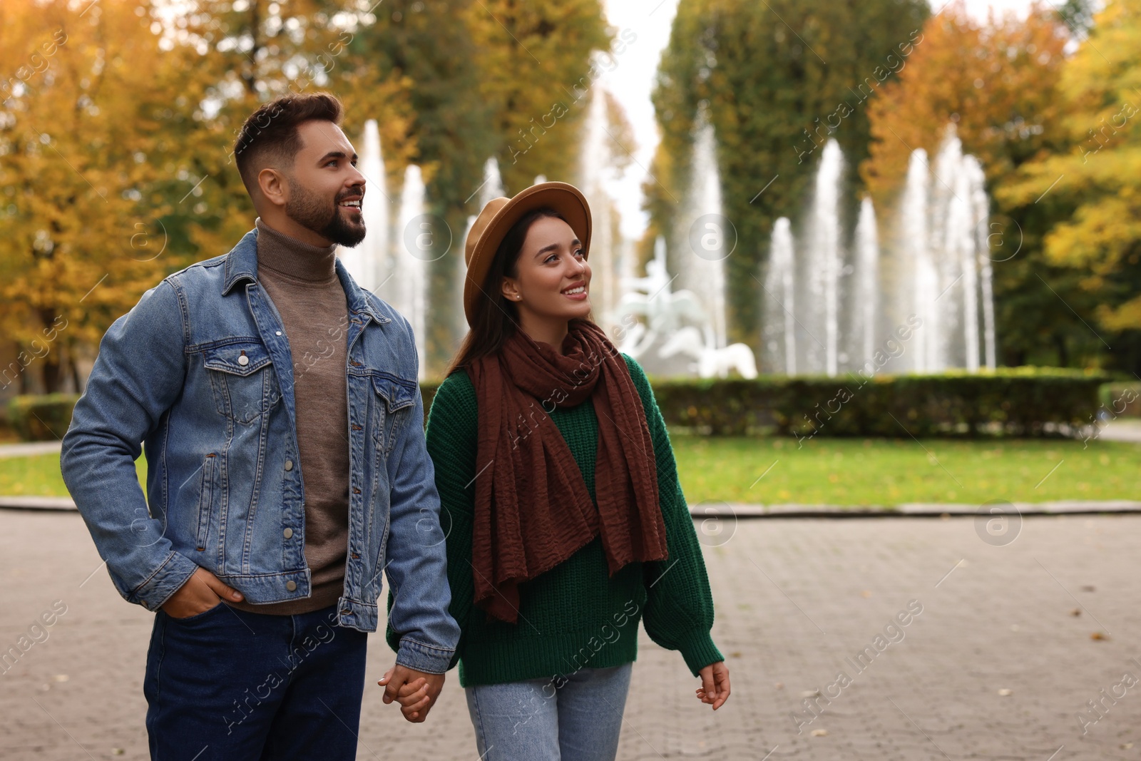 Photo of Romantic young couple spending time together in autumn park, space for text