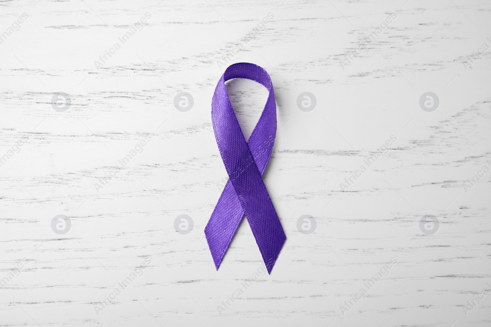 Photo of Purple ribbon on white wooden background, top view. Domestic violence awareness