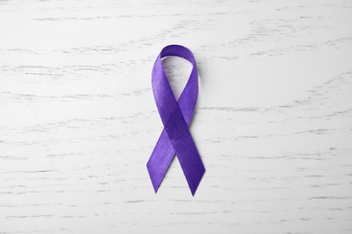Purple ribbon on white wooden background, top view. Domestic violence awareness