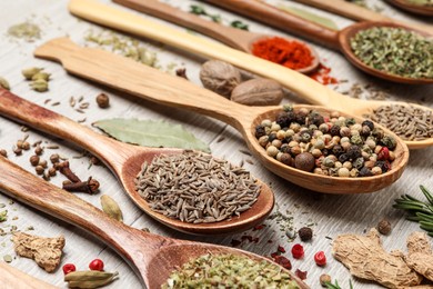 Photo of Different natural spices and herbs on light wooden table, closeup