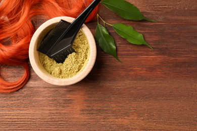 Photo of Bowl of henna powder, brush, green leaves and red strand on wooden table, flat lay with space for text. Natural hair coloring
