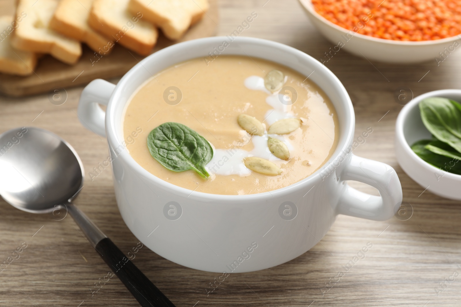 Photo of Healthy cream soup high in vegetable fats on wooden table, closeup