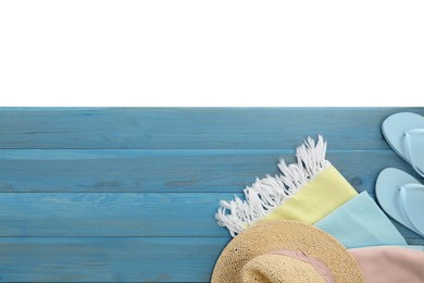 Light blue wooden surface with beach towel, hat and flip flops on white background, top view. Space for text