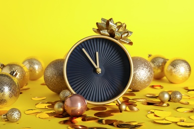 Photo of Stylish clock with Christmas decor on yellow background. New Year countdown