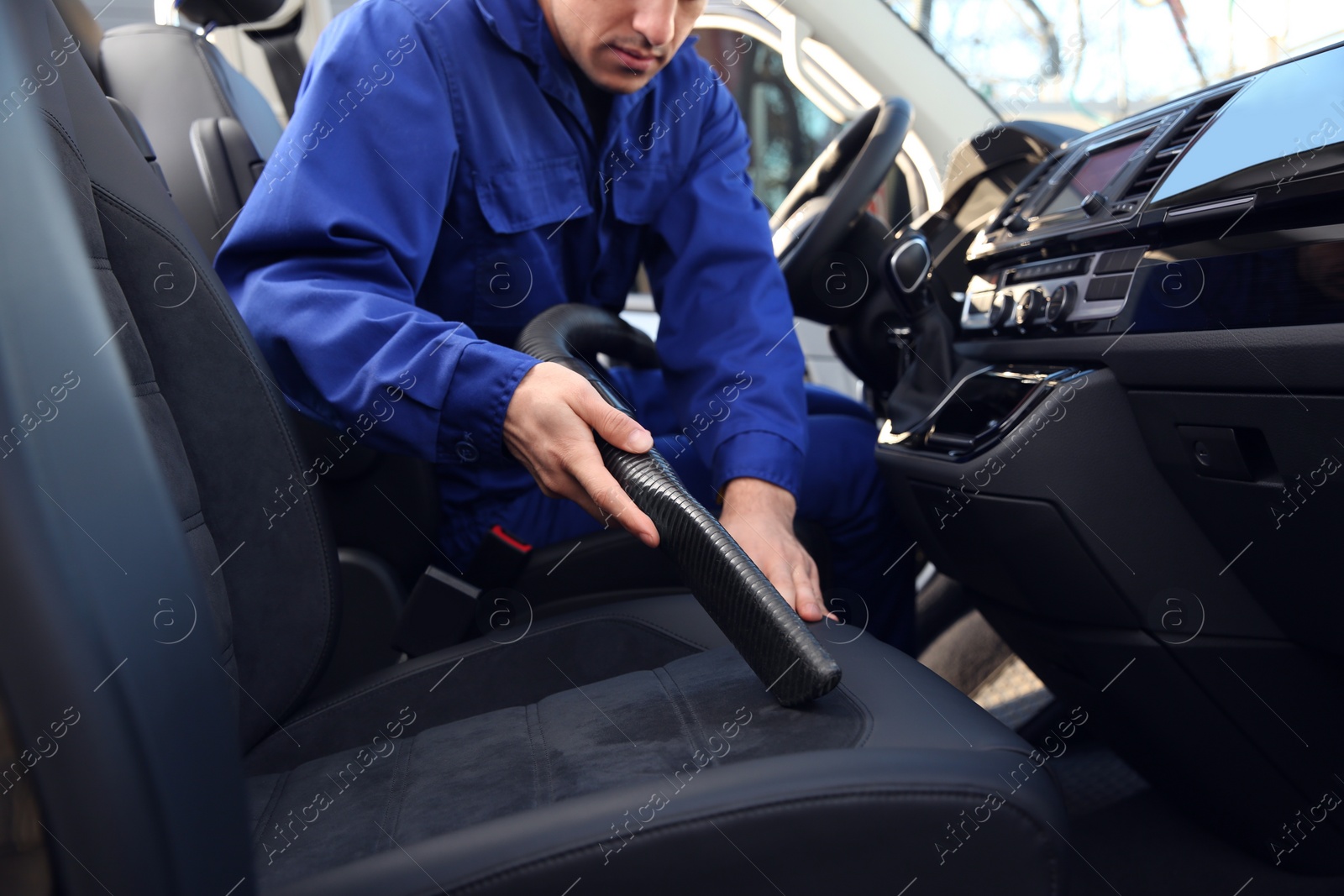 Photo of Car wash worker vacuuming automobile seat, closeup