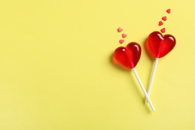 Photo of Sweet heart shaped lollipops and sprinkles on yellow background, flat lay with space for text. Valentine's day celebration