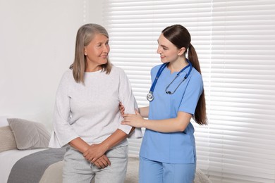 Young healthcare worker assisting senior woman indoors