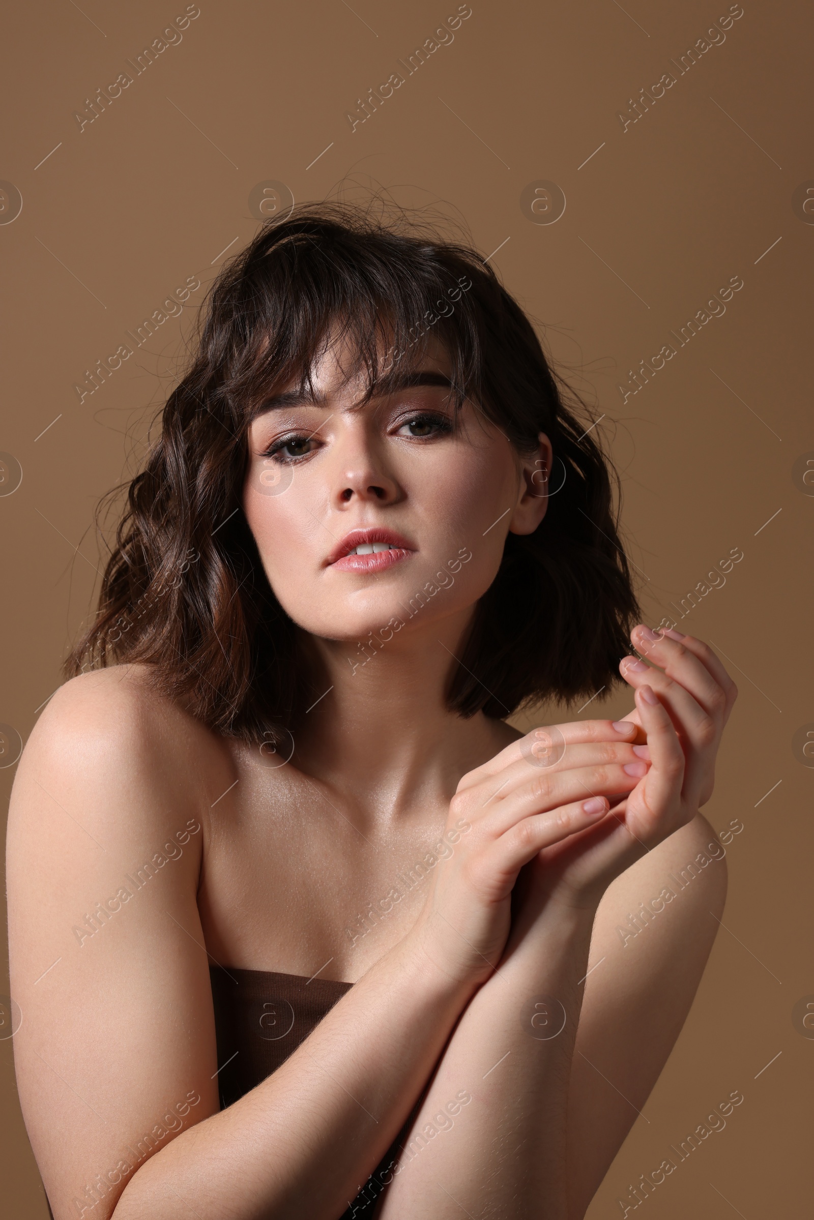 Photo of Portrait of beautiful young woman with wavy hairstyle on brown background