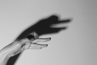 Shadow puppet. Woman making hand gesture like goose on light background, closeup with space for text. Black and white effect