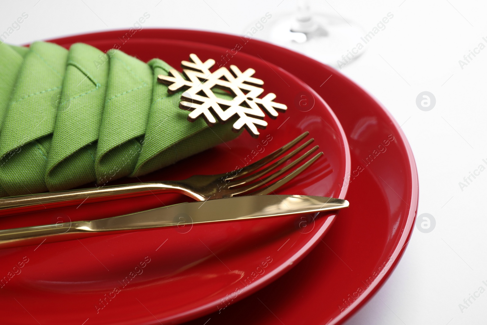 Photo of Festive table setting with green napkin folded in shape of Christmas tree on white background, closeup