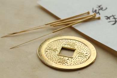 Photo of Acupuncture needles and Chinese coin on paper, closeup