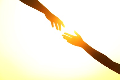 Photo of Silhouettes of man and woman helping each other against sunset, closeup