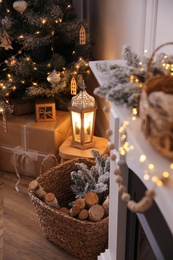 Photo of Basket with wood near fireplace and Christmas tree indoors. Interior element