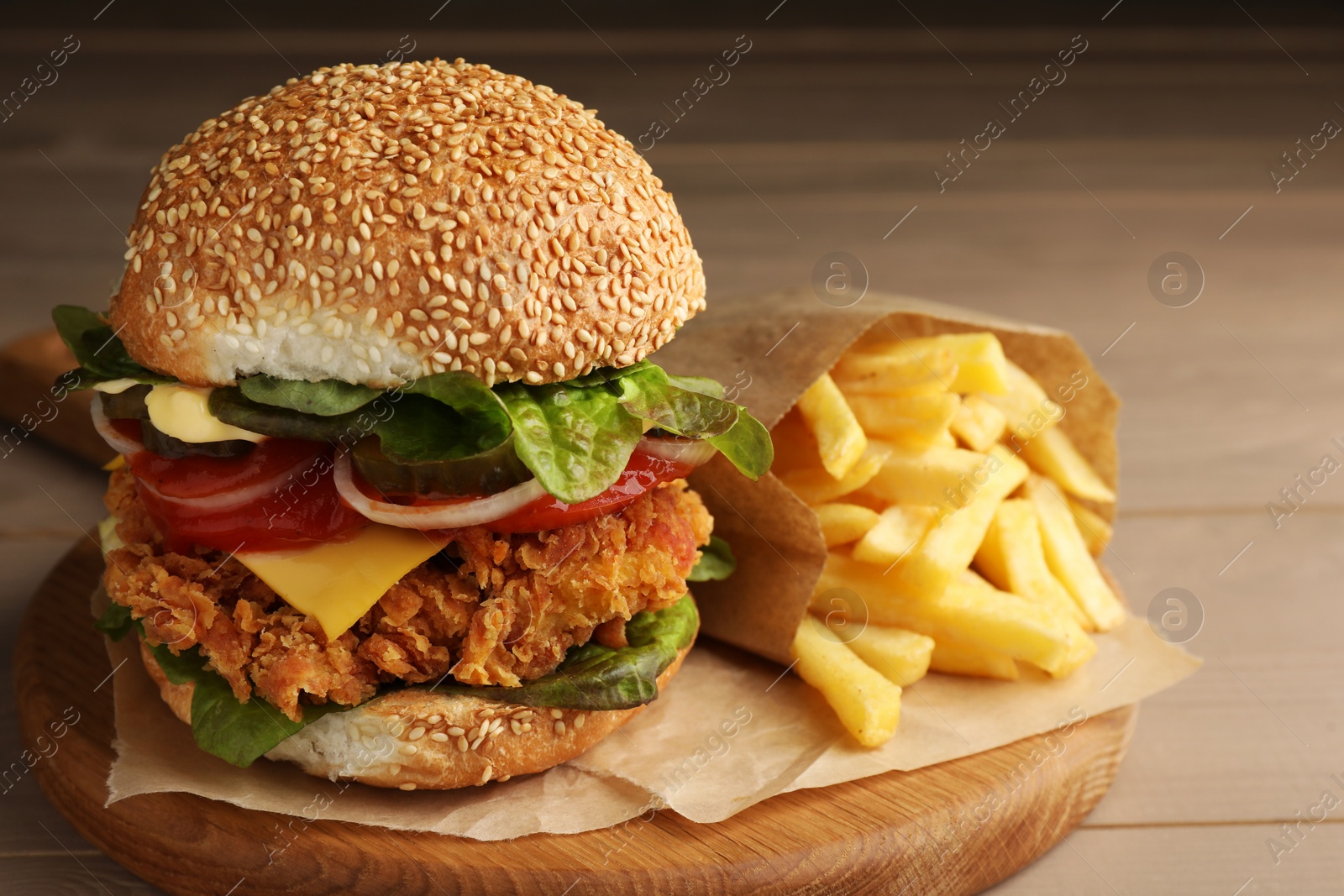 Photo of Delicious burger with crispy chicken patty and french fries on wooden table, closeup