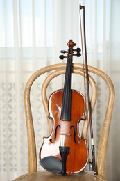 Photo of Classic violin and bow on chair indoors