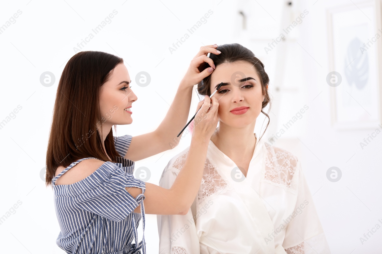 Photo of Professional makeup artist working with young woman in salon