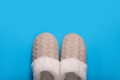 Pair of beautiful soft slippers on light blue background, top view. Space for text